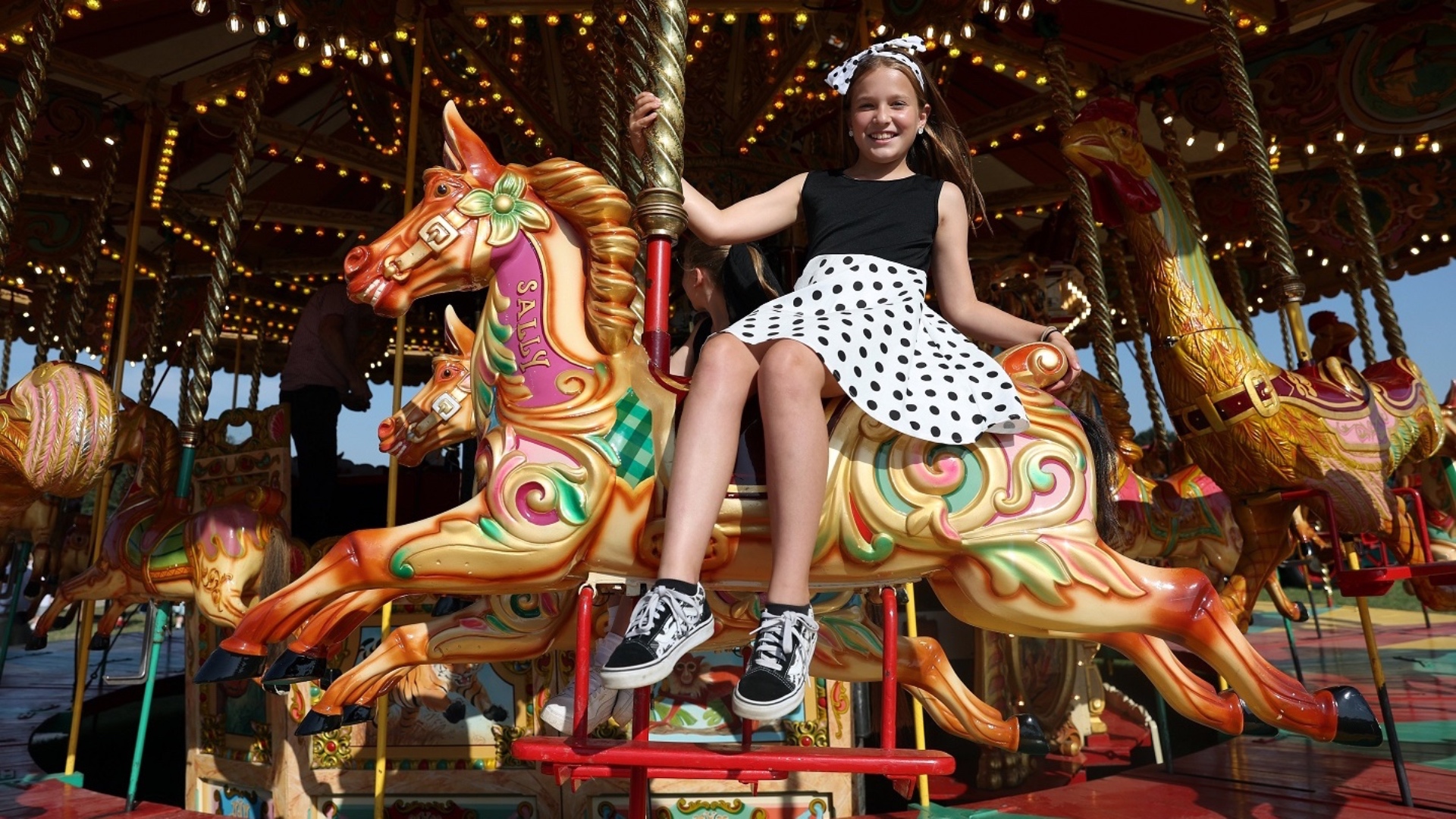 A visitor enjoying the vintage funfair at the 2023 Goodwood Revival. Ph. by PA.