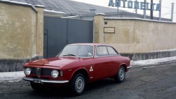 Anni ’60. Un’Alfa Romeo Giulia Sprint GTA davanti al cancello dell’Autodelta, il reparto corse della casa milanese che ne curava la messa a punto
